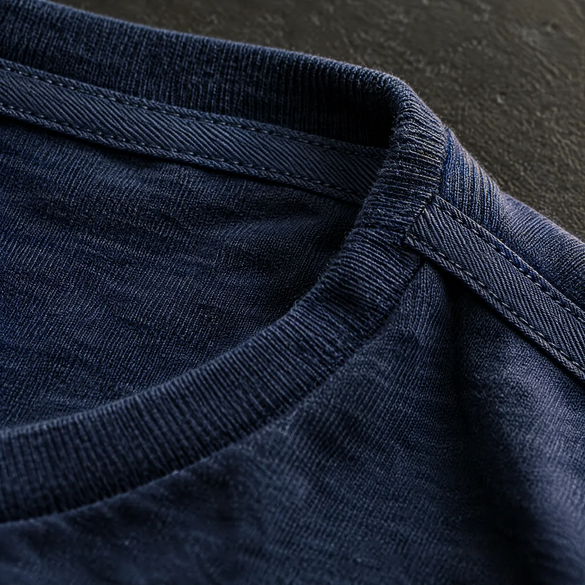 Macro view of tape covering a shoulder seam inside a T-shirt.