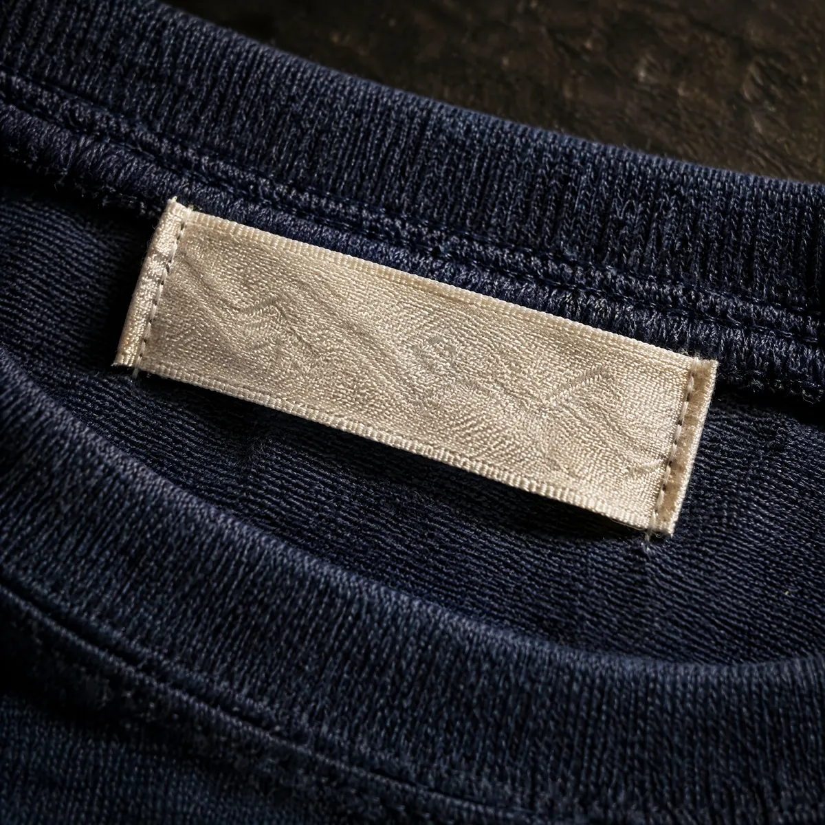 Macro view of a plain woven neck label stitched into a garment.